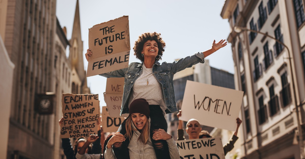 A racially diverse group of women holding various cardboard protest signs as they fight for the rights of women.